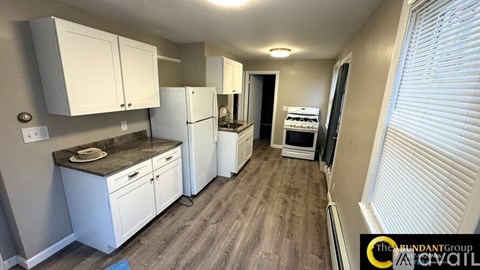 A kitchen with white cabinets and a wooden floor.