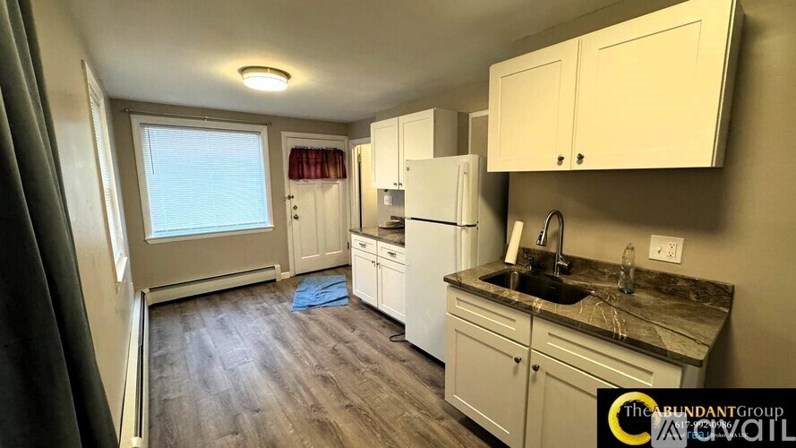 A kitchen with white appliances and cabinets is available for rent.