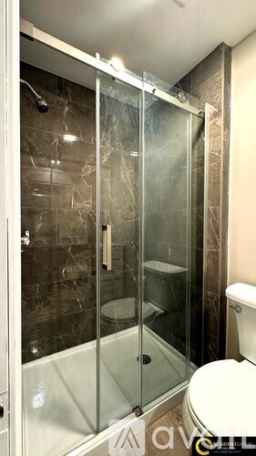 A shower area with a glass door and a tiled wall.