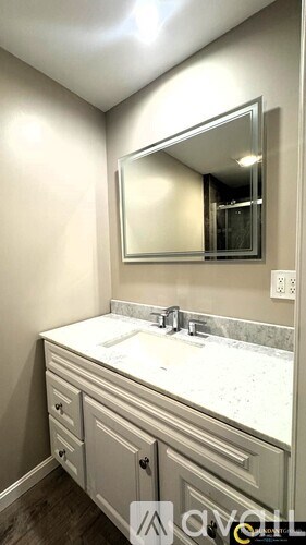 A bathroom vanity with a marble countertop and a large mirror above it.