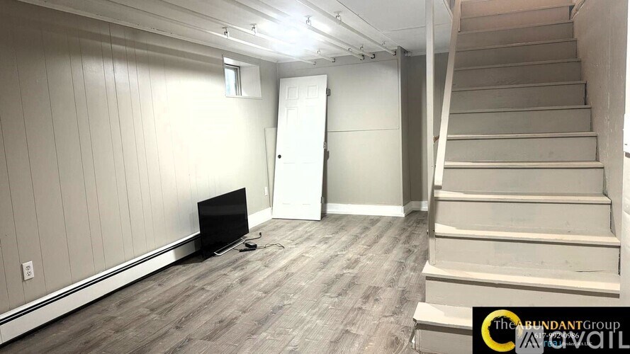 A room with a staircase and a flat screen TV.