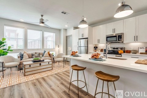 A kitchen with a bar stool and a countertop with a microwave and oven.