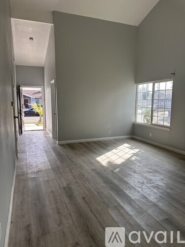 A room with wooden flooring and a window on the right side.