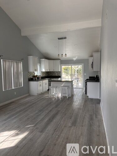 A spacious kitchen with white cabinets and a dining area with a table and chairs.