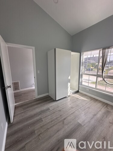 A room with grey walls and wooden flooring, with a door and a window.