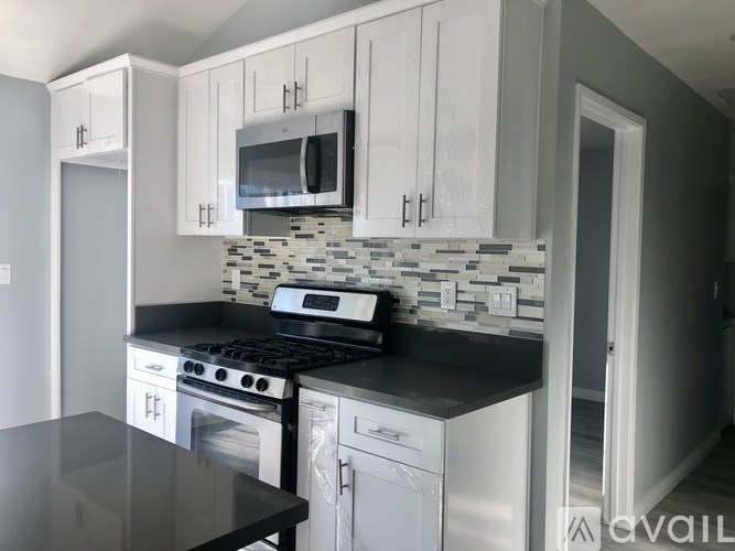A kitchen with white cabinets and a black countertop.