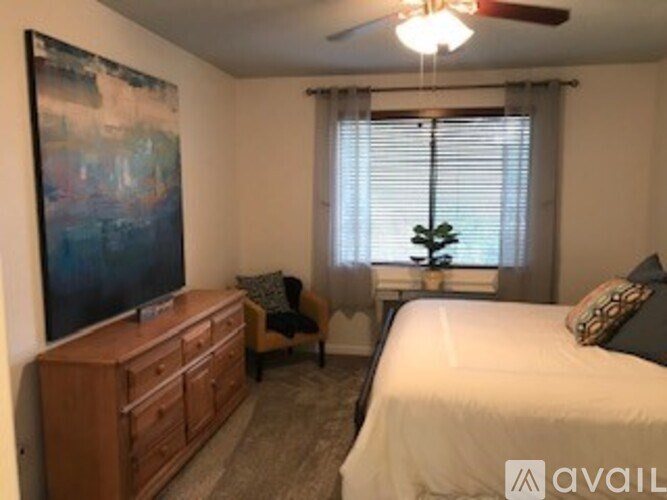 A bedroom with a bed, a dresser, a chair, and a painting on the wall.