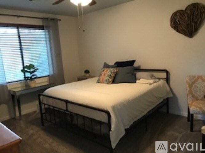 A bedroom with a bed, a chair, and a heart-shaped decoration on the wall.
