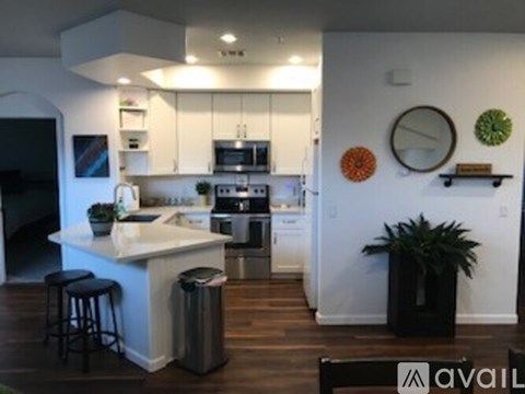 A kitchen with white cabinets and a white island with a plant on it.
