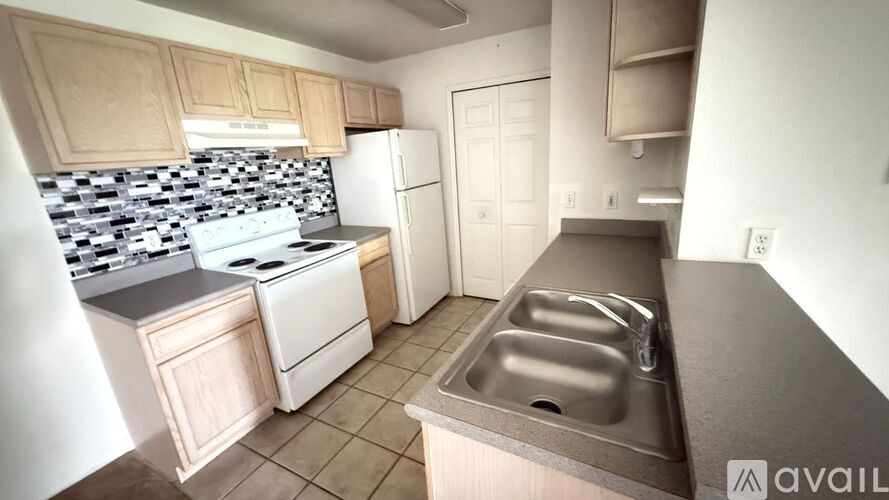 A kitchen with a white stove top oven, white refrigerator, and a black and white tiled backsplash.