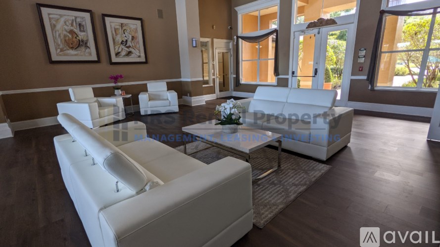 A living room with white furniture and a glass coffee table.