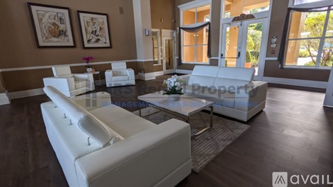 A living room with white furniture and a glass coffee table.