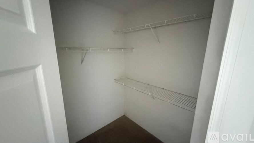 A small, empty closet with a white door on the left.