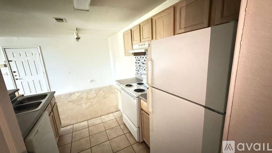 A kitchen with a white refrigerator and a white door.