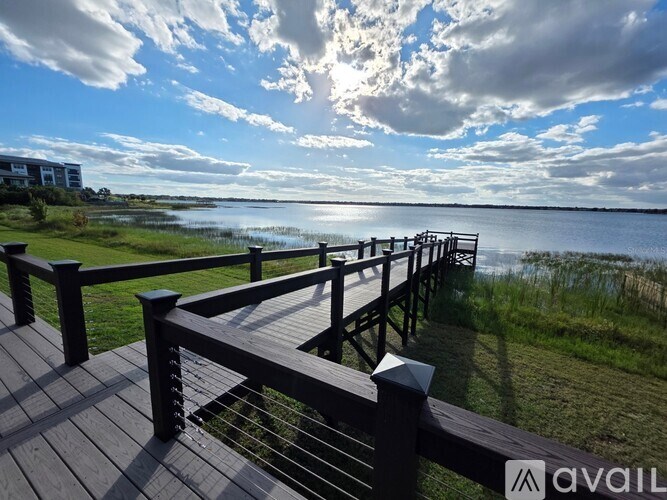 A wooden deck overlooks a body of water with a partly cloudy sky above.