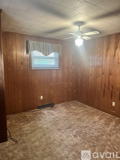 A room with wooden walls and a ceiling fan.