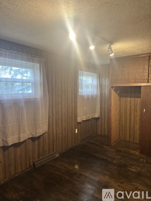 A room with wooden walls and a window with curtains.