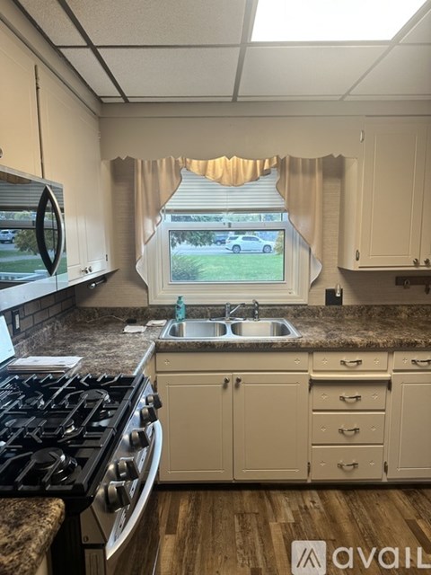 A kitchen with a black stove top oven and a window with curtains.