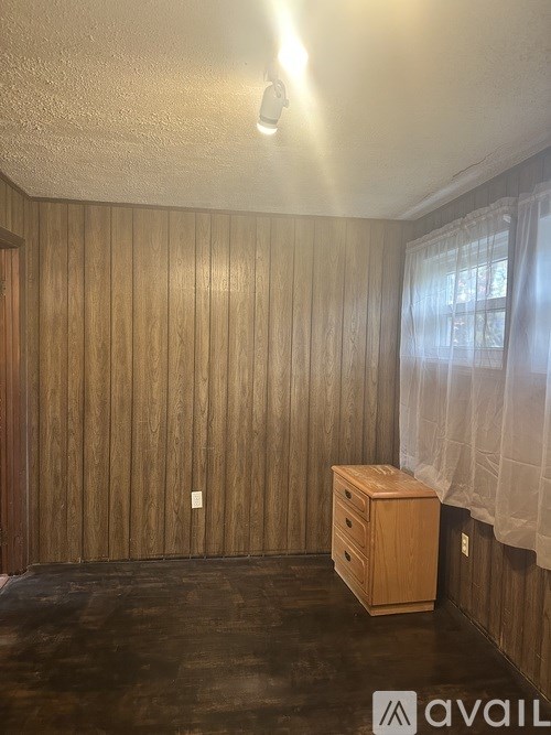 A room with wooden walls and a wooden chest of drawers.