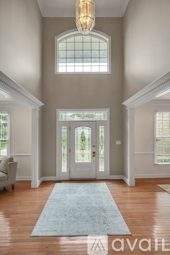 A large foyer with a rug and a chandelier.