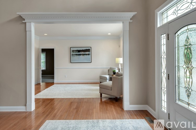 A living room with a white couch and a painting on the wall.