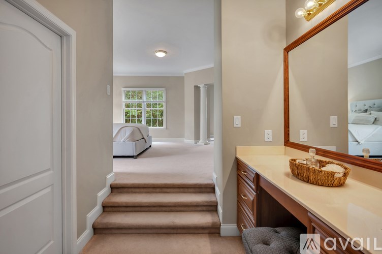A hallway with a staircase leading to a bedroom with a window.
