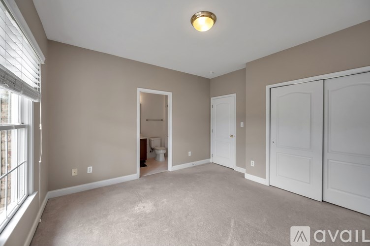 A room with a carpeted floor and a window with blinds.