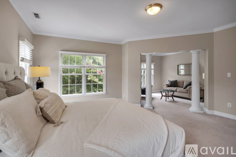 A bedroom with a large bed and a window with blinds.