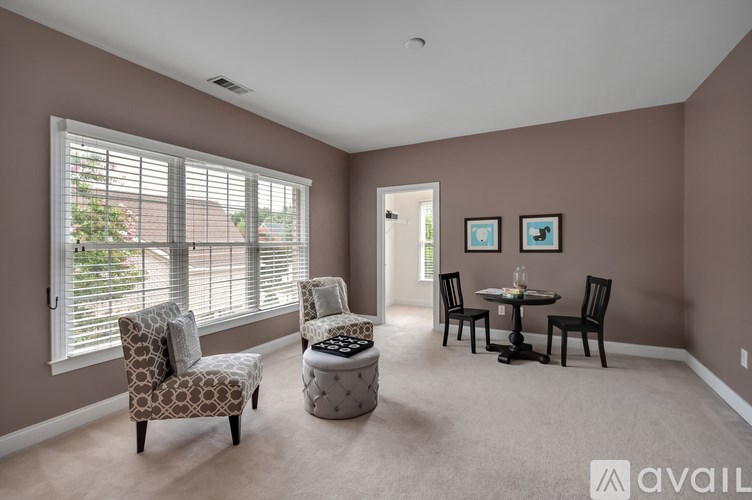 A living room with a chair, ottoman, and table.