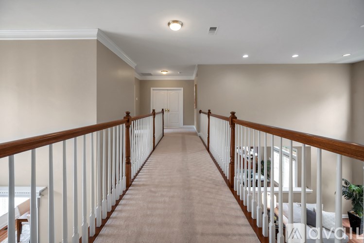 A long hallway with a white railing and brown trim.