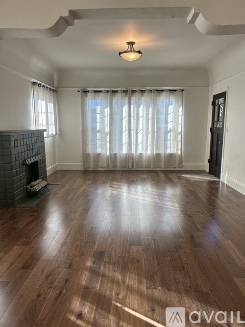 A room with wooden flooring and a fireplace.