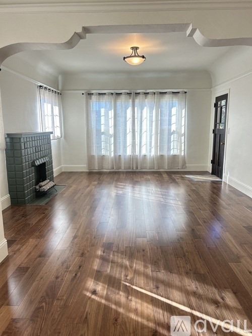 A spacious living room with wooden flooring and a fireplace.