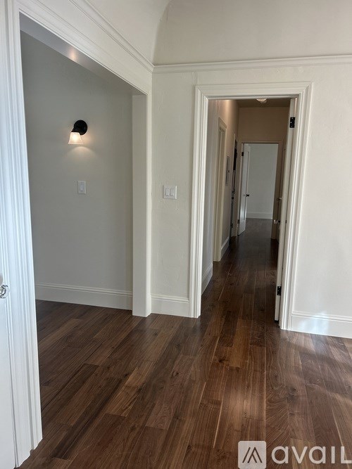 A hallway with wood floors and white walls.