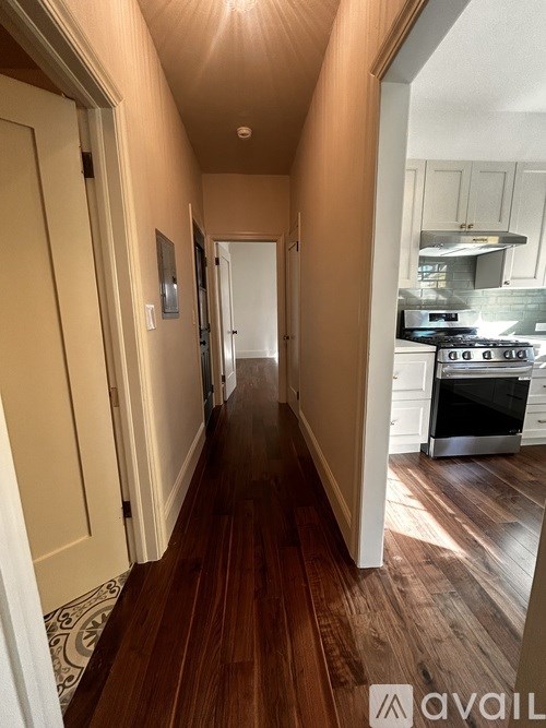 A long hallway with a kitchen in the background.