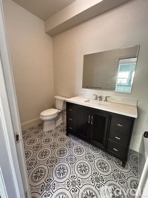 A bathroom with a toilet, sink and black cabinets.