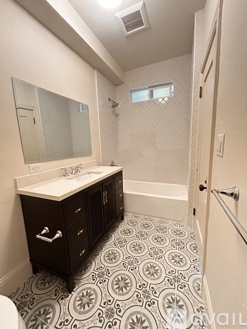 A bathroom with a patterned floor and a white sink.
