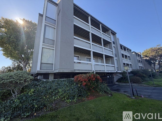 A modern apartment building with a well-maintained lawn and trees in front.