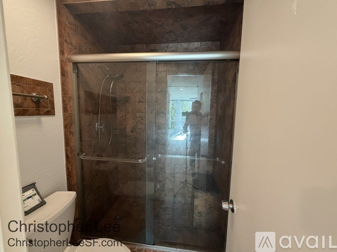 A bathroom with a glass shower door and a toilet.