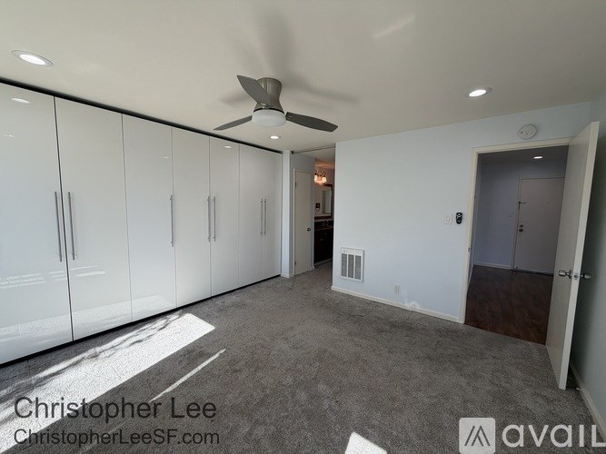 A room with a ceiling fan and white cabinets.