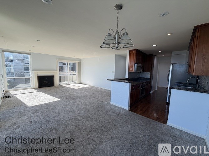 A large, empty living room with a fireplace and a chandelier.