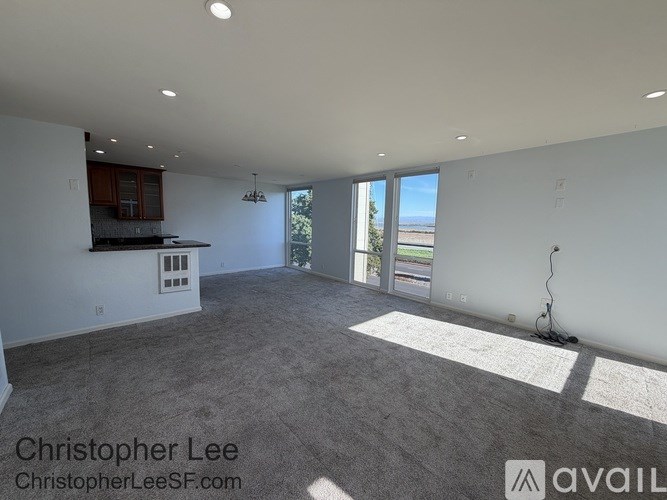 A spacious living room with a kitchenette and sliding glass doors leading to a balcony.