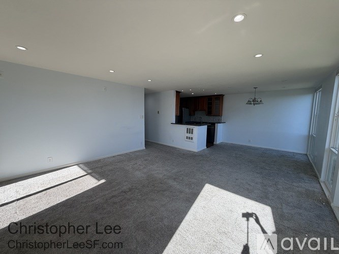 A large empty room with a grey carpet and white walls.