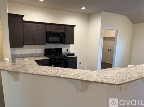 A kitchen with granite countertops and dark brown cabinets.