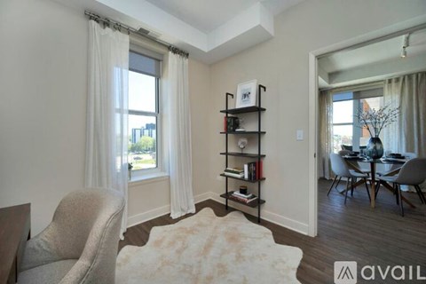 A living room with a grey armchair and a bookshelf filled with books.