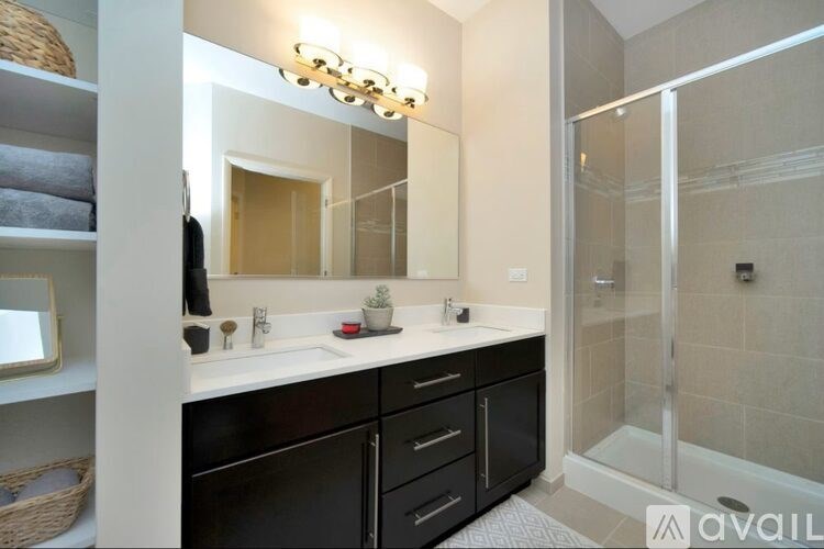 A bathroom with a vanity, mirror, and a glass shower stall.