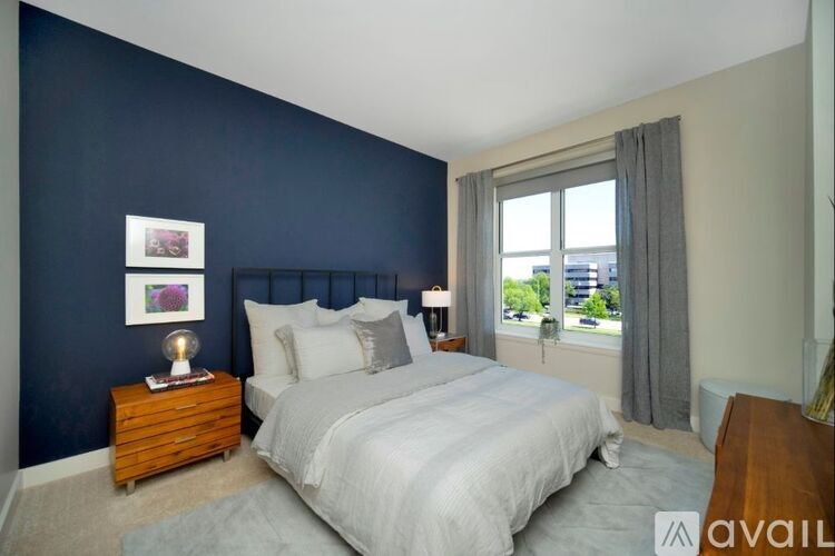 A bedroom with a large bed and a window overlooking a cityscape.