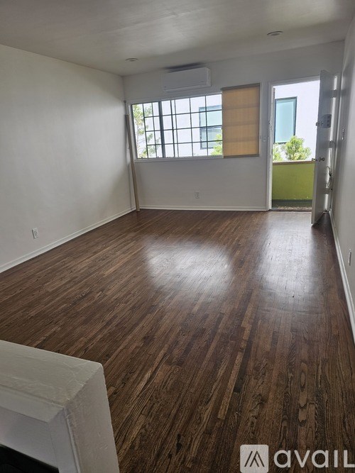 A room with wooden flooring and a window with blinds.