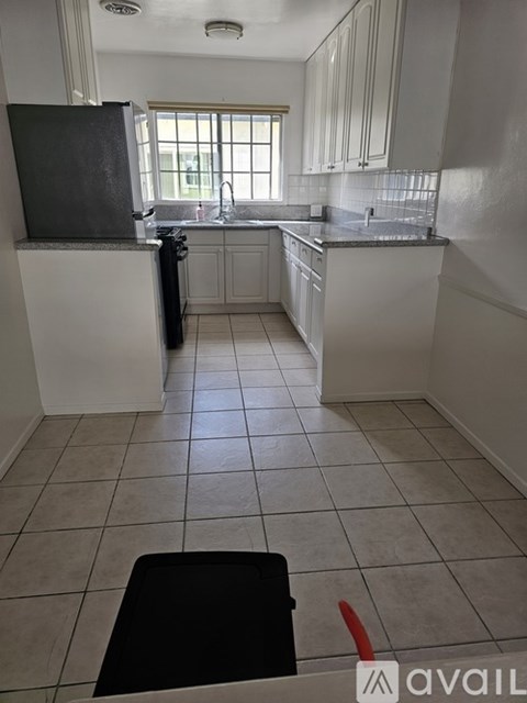 A kitchen with white cabinets and a black fridge.