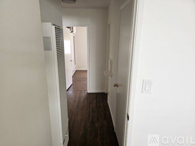A hallway with a white door and a white wall.