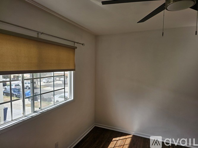 A room with a window covered by a yellow blind and a ceiling fan.
